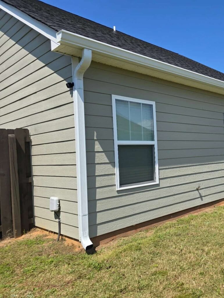 Home with newly installed white seamless aluminum gutter and downspout designed to improve drainage and protect the siding in Middle Georgia.
